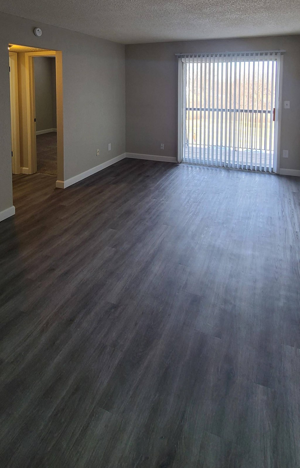 an empty living room with wooden floors and a window