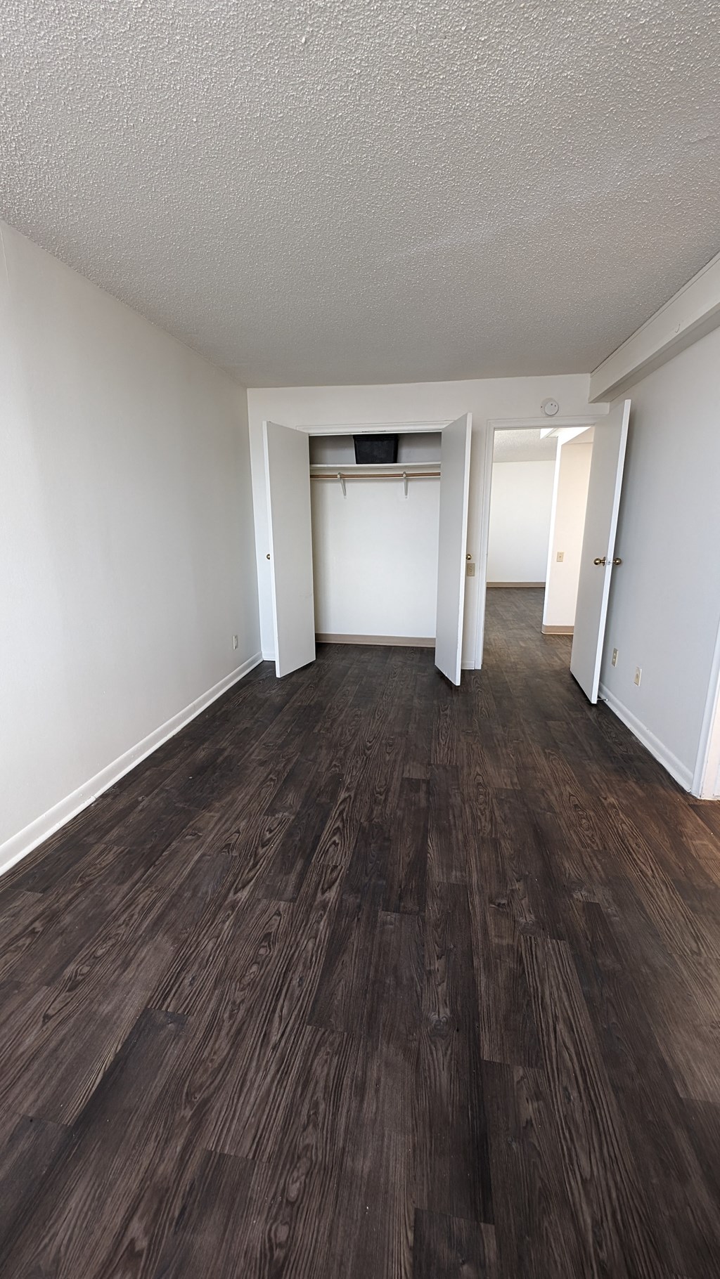 an empty living room with wooden floors and white walls