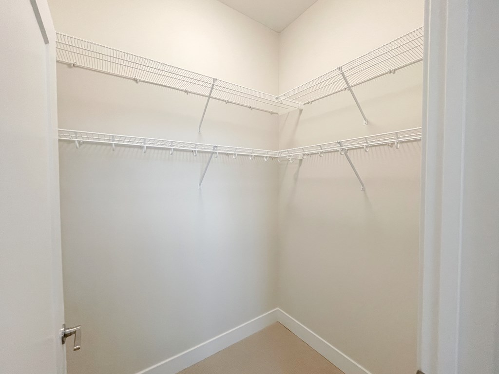 an empty closet with white walls and shelves and a white door