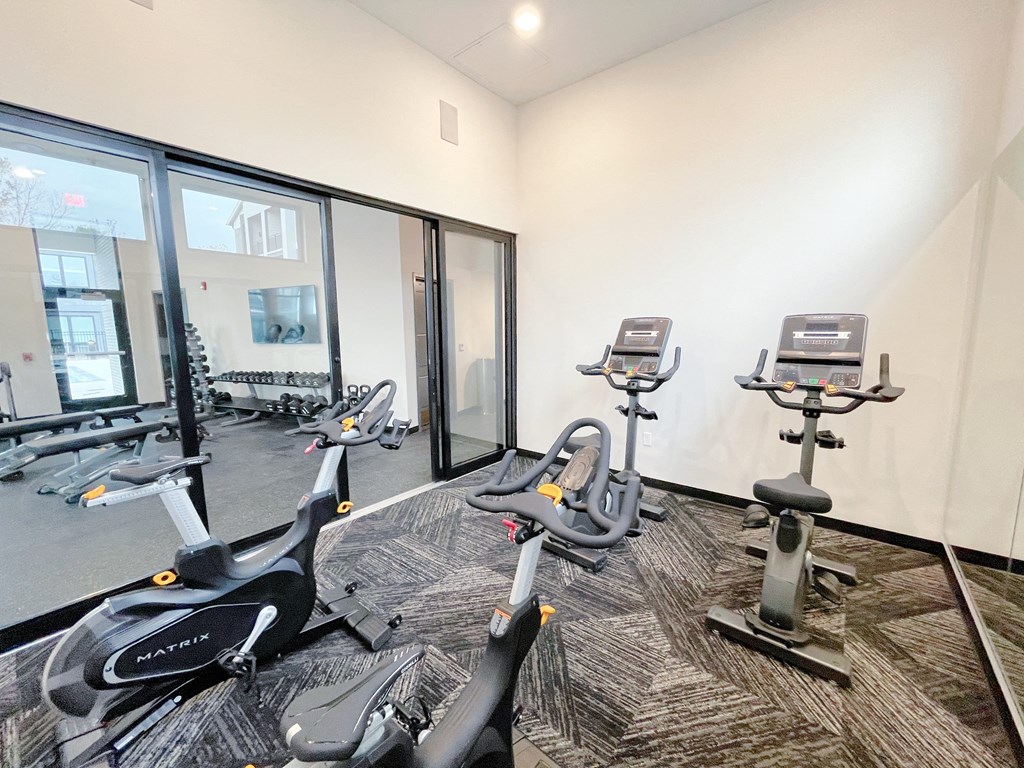 a gym with cardio machines and windows at the district at highland village apartments