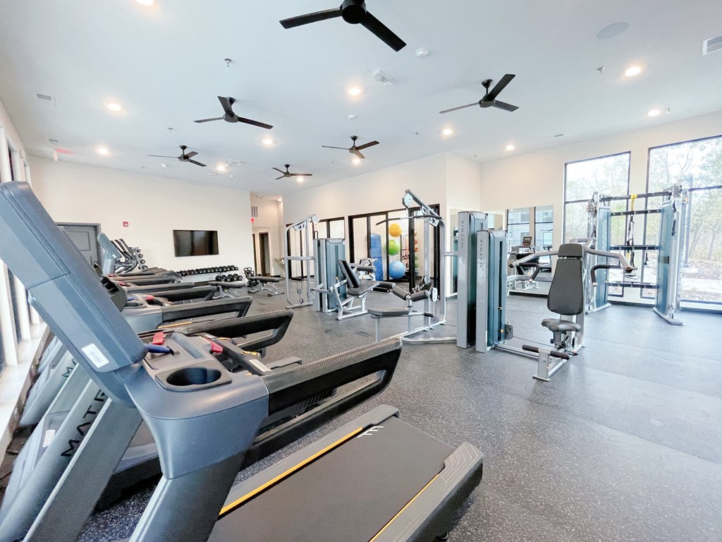 a gym with treadmills and other exercise equipment in a building with windows
