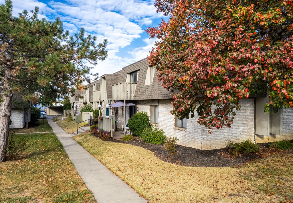 a sidewalk in front of a white brick apartment building