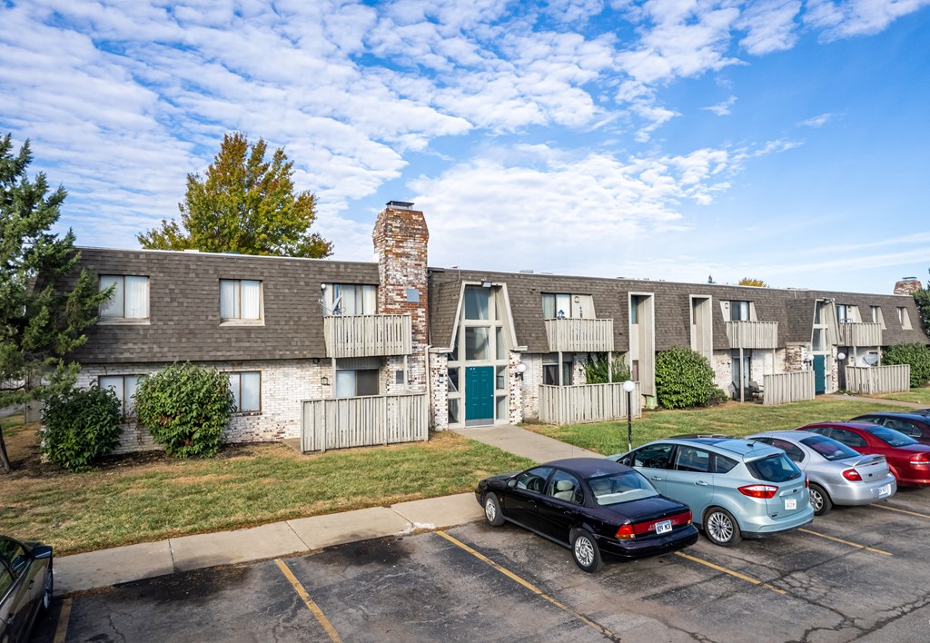 a parking lot with cars in front of an apartment building
