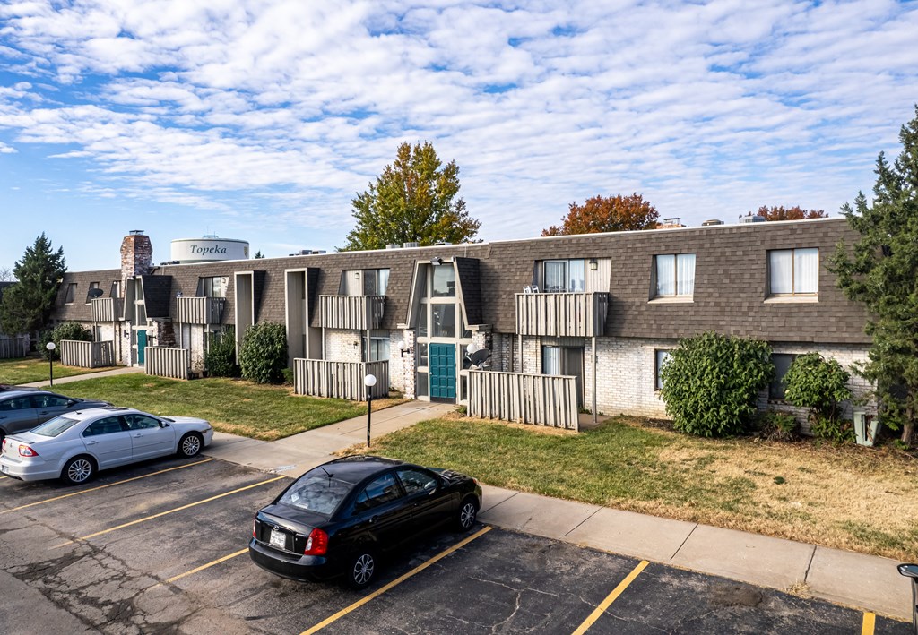 a parking lot with cars in front of an apartment building
