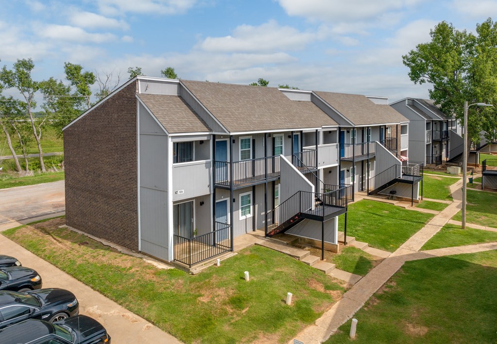 an aerial view of a row of apartment buildings with a parking lot in the foreground at Residences at Lakeshore Apartments, Oklahoma City, 73132