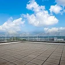 A rooftop with a grid of tiles and a metal railing.