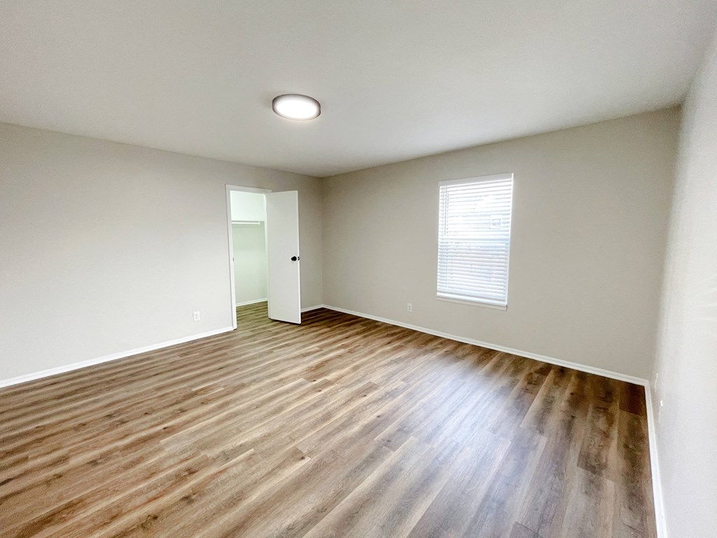 an empty living room with wood floors and white walls