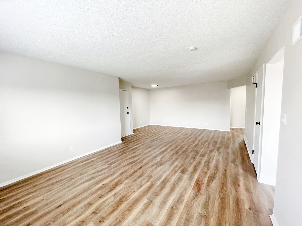 an empty living room with wood floors and white walls
