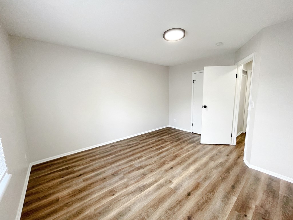 an empty living room with wood flooring and white walls