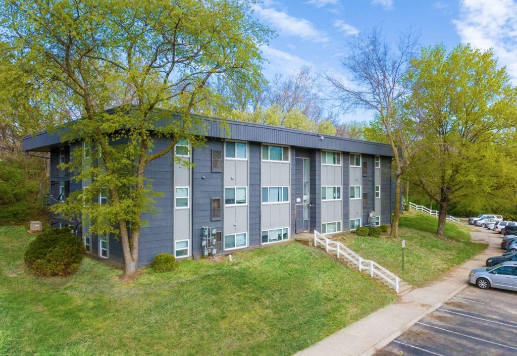 a gray building with green trees in the background