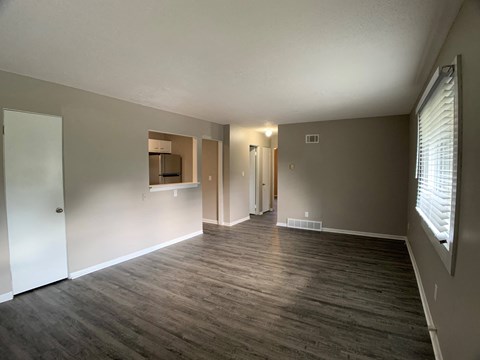 an empty living room with wood flooring and a large window