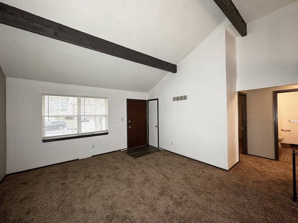 the living room of an empty house with carpet and a window