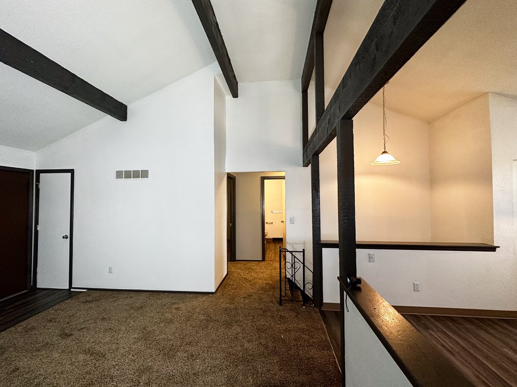 a living room with white walls and exposed wood beams
