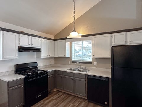 an empty kitchen with black appliances and white cabinets