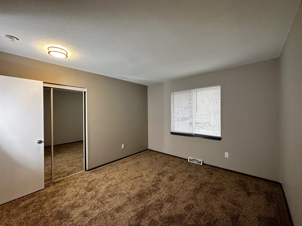 an empty room with a window and a closet