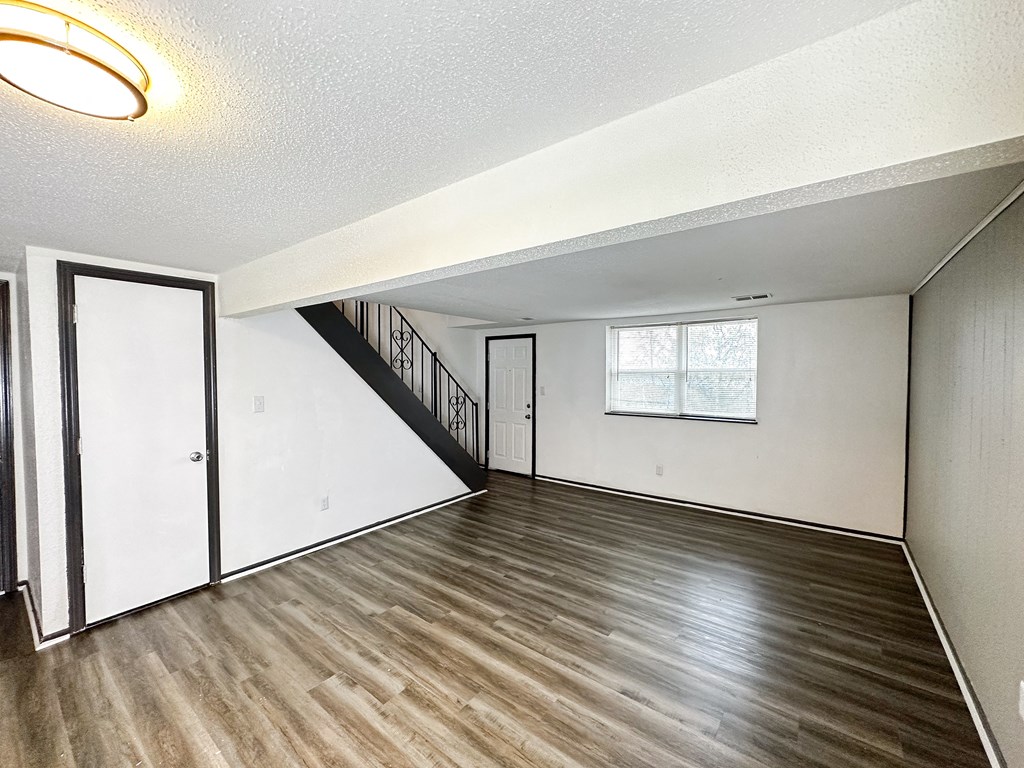 the living room and dining room of an empty home with wood flooring