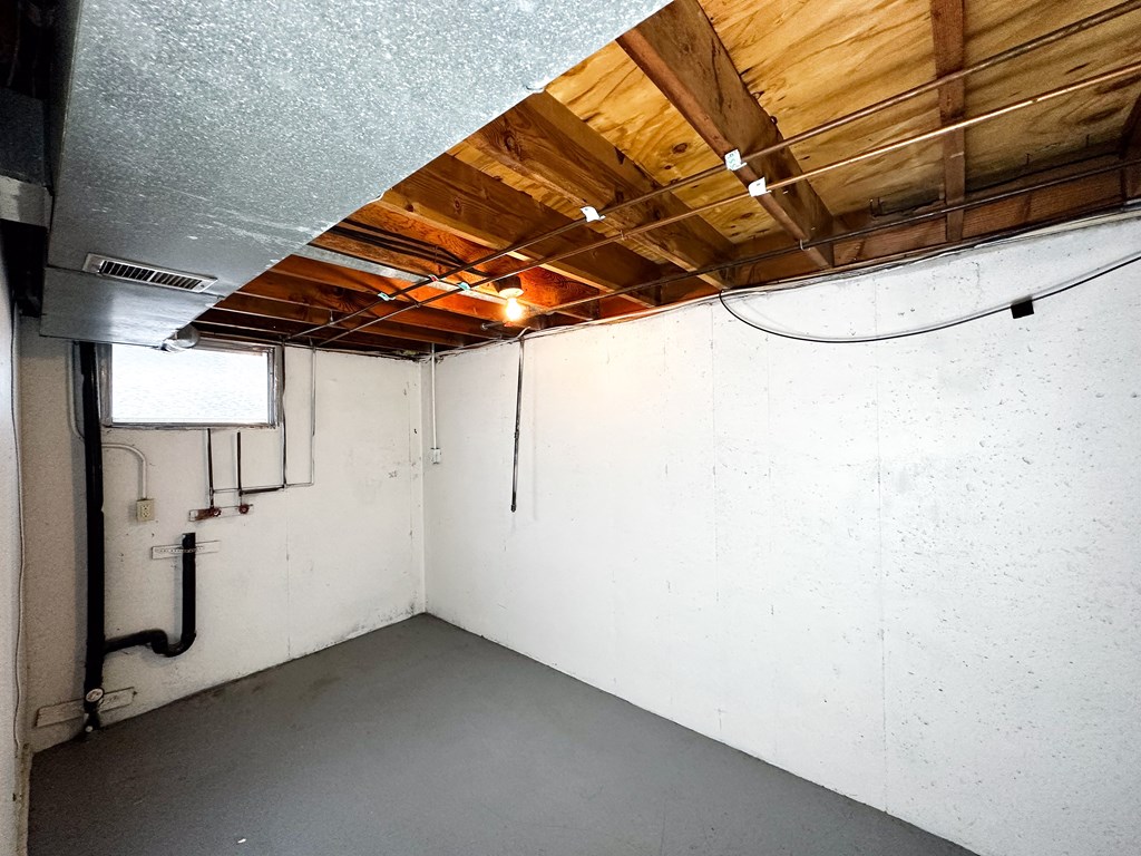 the inside of a basement with a white wall and wood ceilings