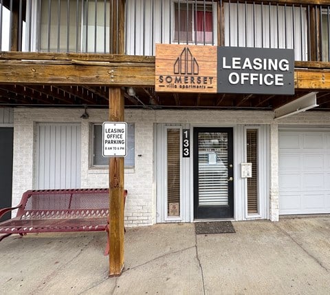 a building with a bench and a leasing office sign