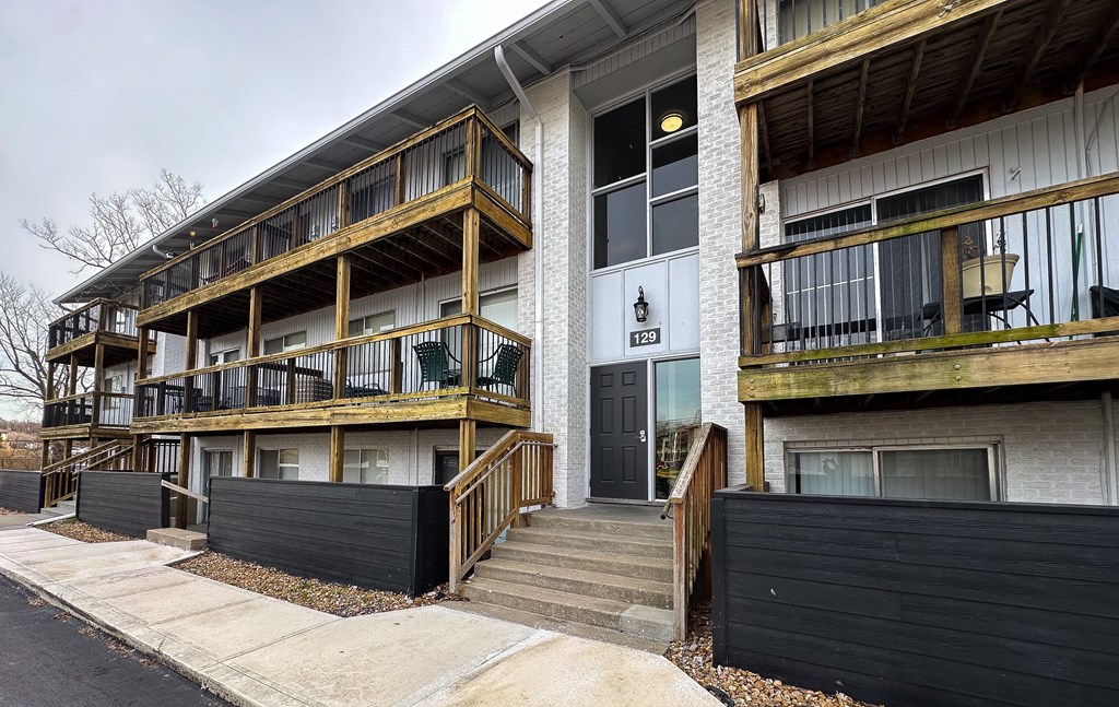 the exterior of an apartment building with stairs and a black fence