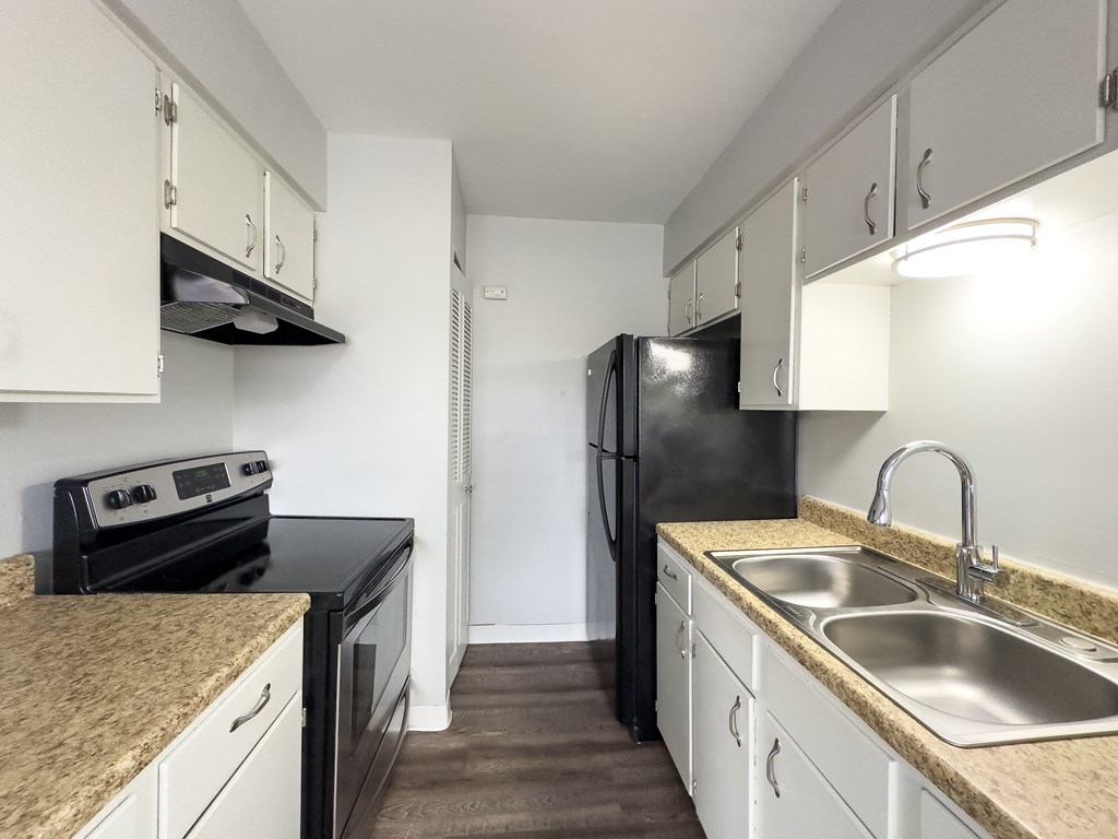 a kitchen with white cabinets and black appliances and granite counter tops