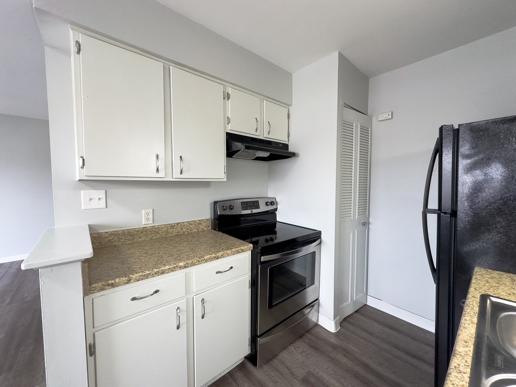 a kitchen with white cabinets and a black stove and refrigerator