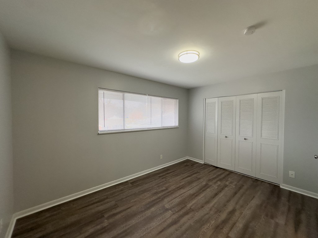 an empty living room with a window and a closet
