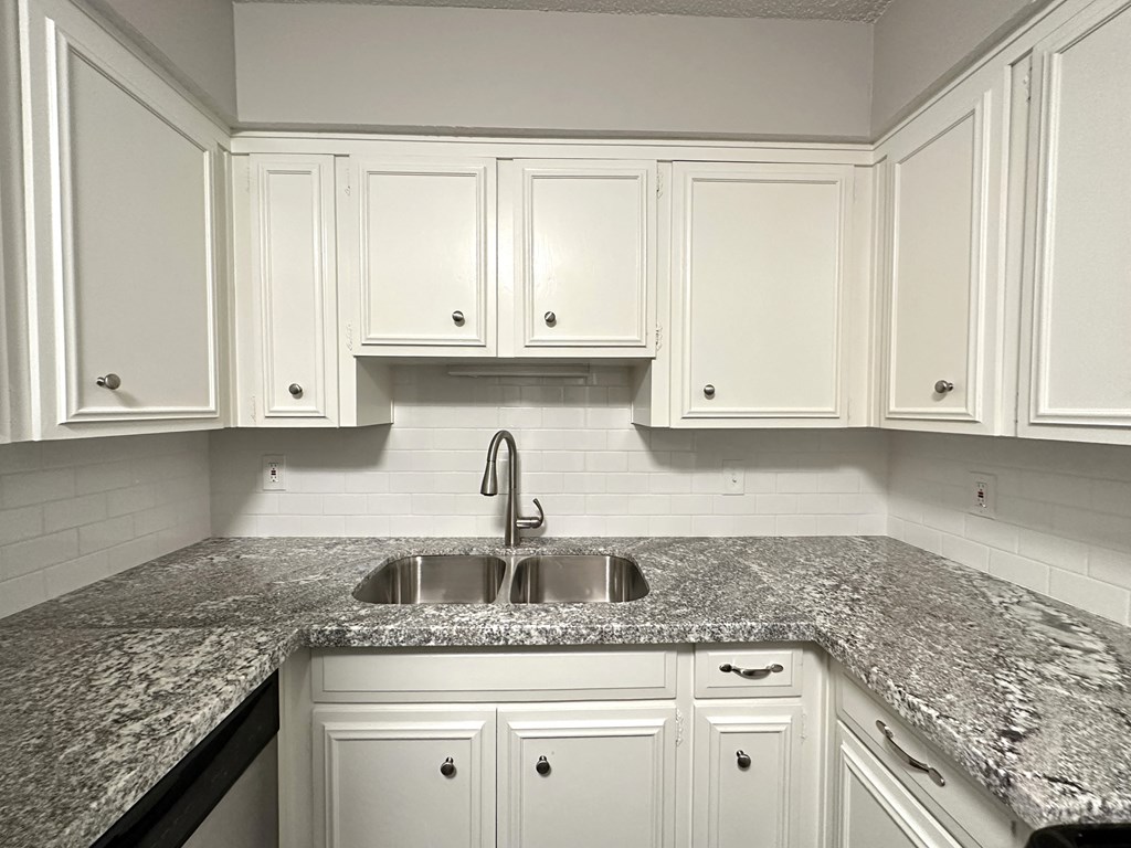 a kitchen with marble counter tops and white cabinets