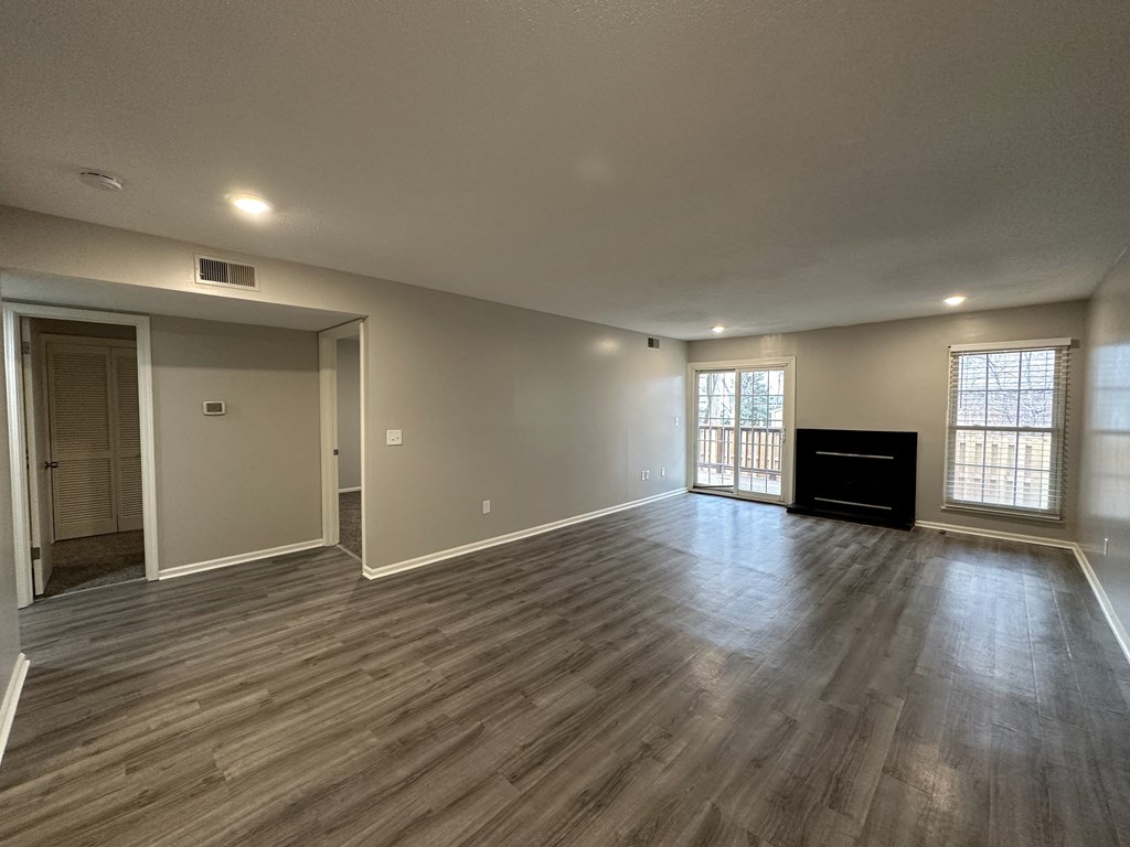 an empty living room with wood floors and a fireplace