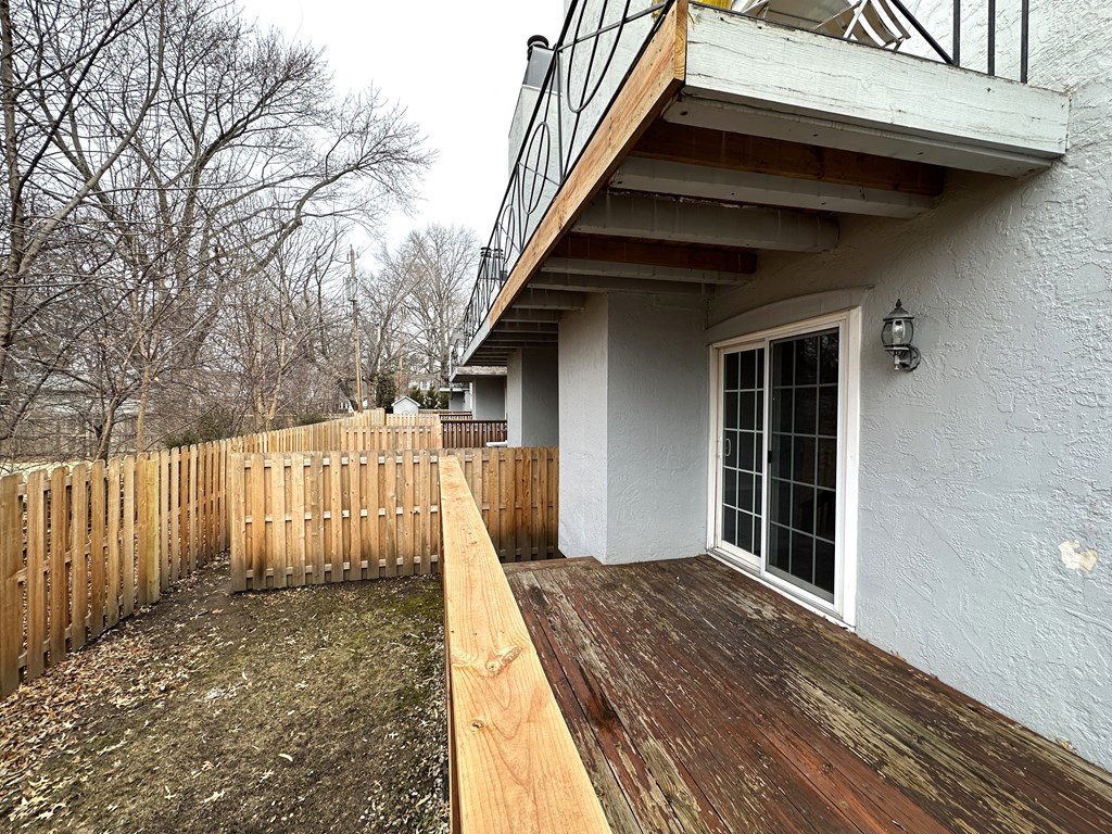 a deck in front of a house with a wooden fence