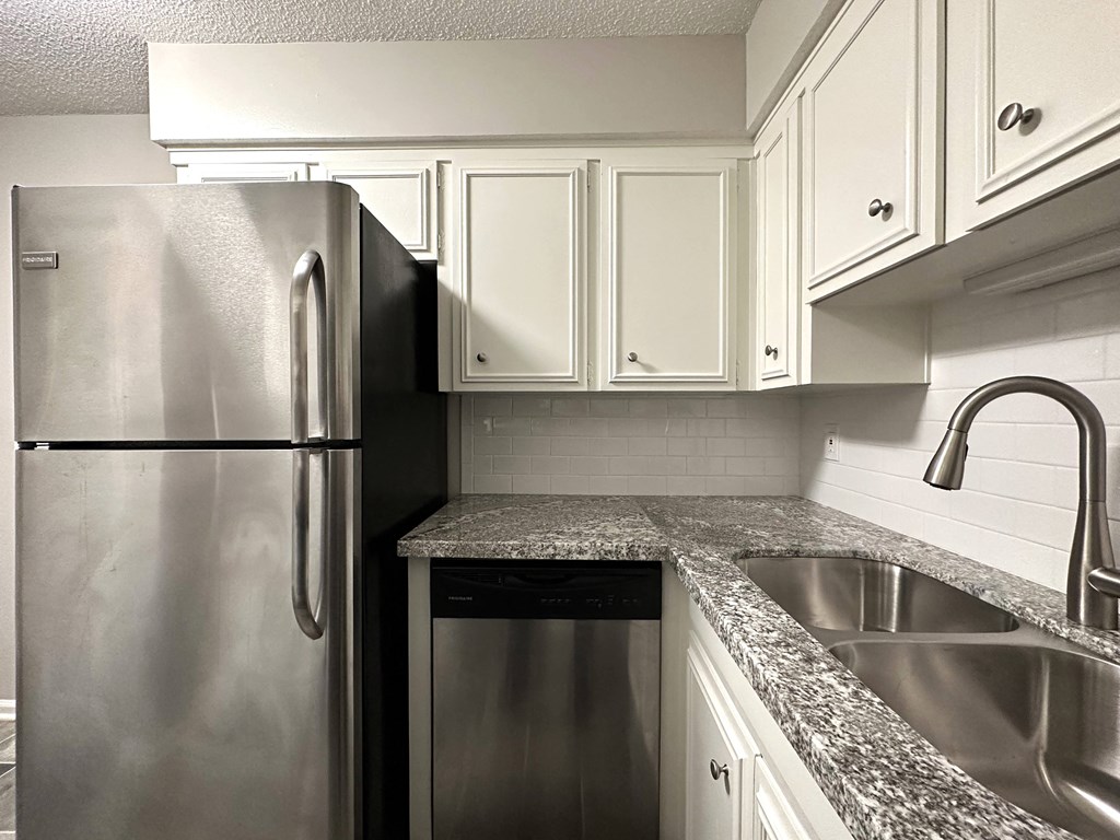 a kitchen with white cabinets and a stainless steel refrigerator