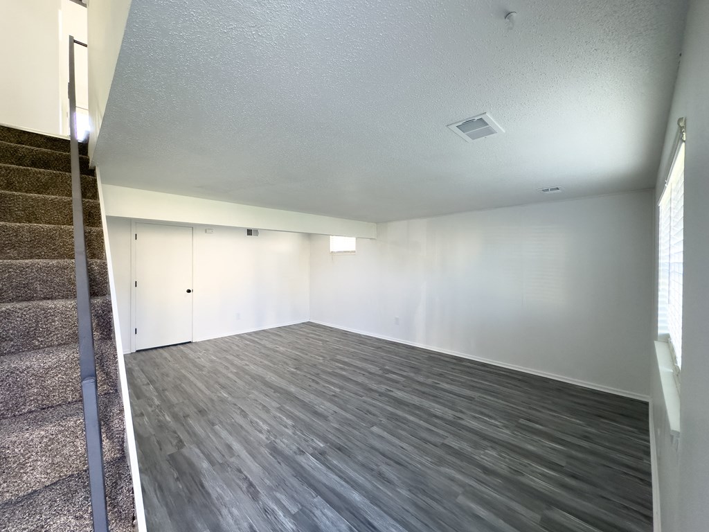 an empty living room with wood flooring and white walls