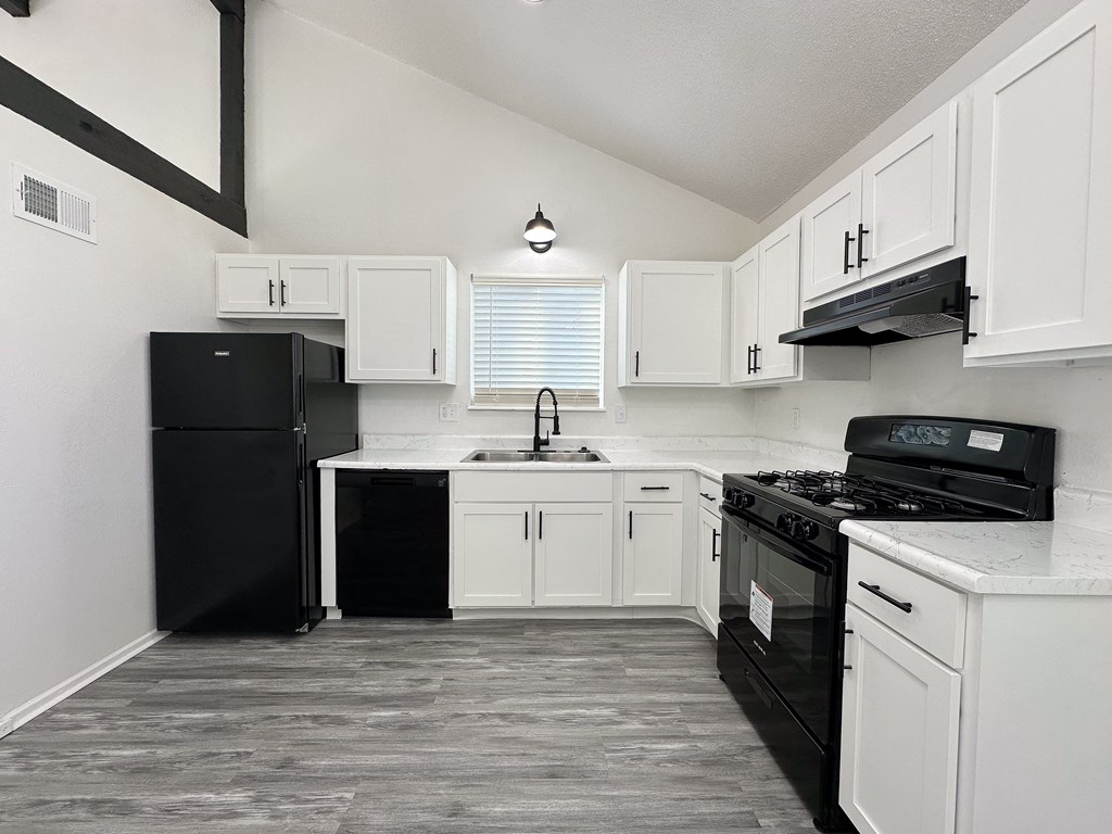 an empty kitchen with white cabinets and black appliances