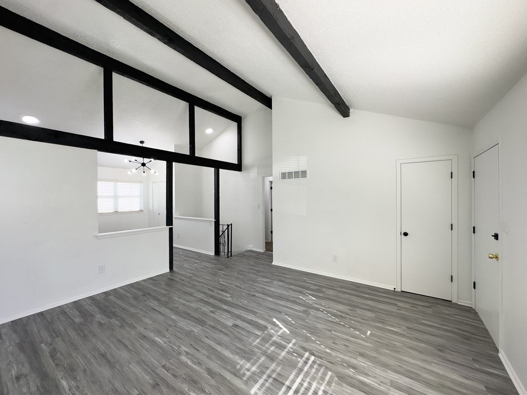 the living room of a new home with white walls and wood flooring