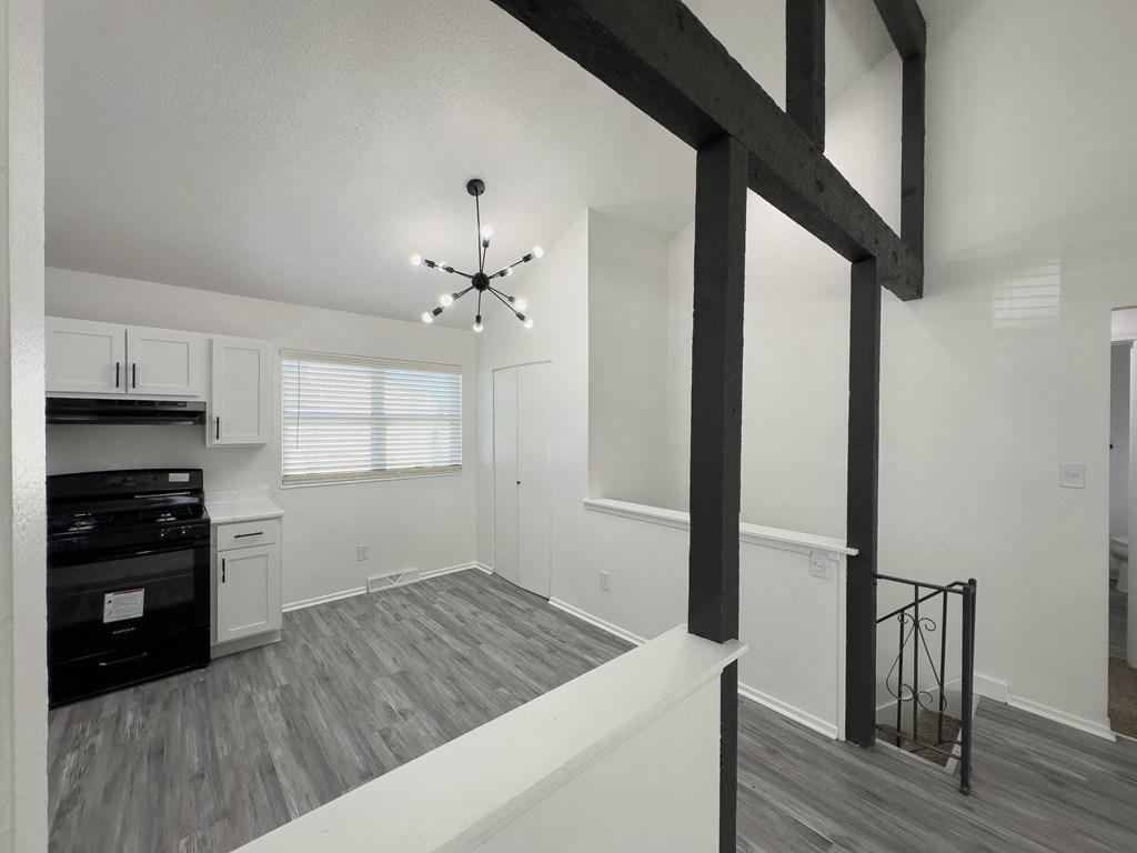 the living room and kitchen of an apartment with white walls and black appliances