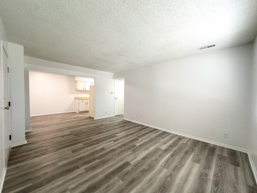 an empty living room with wood flooring and white walls