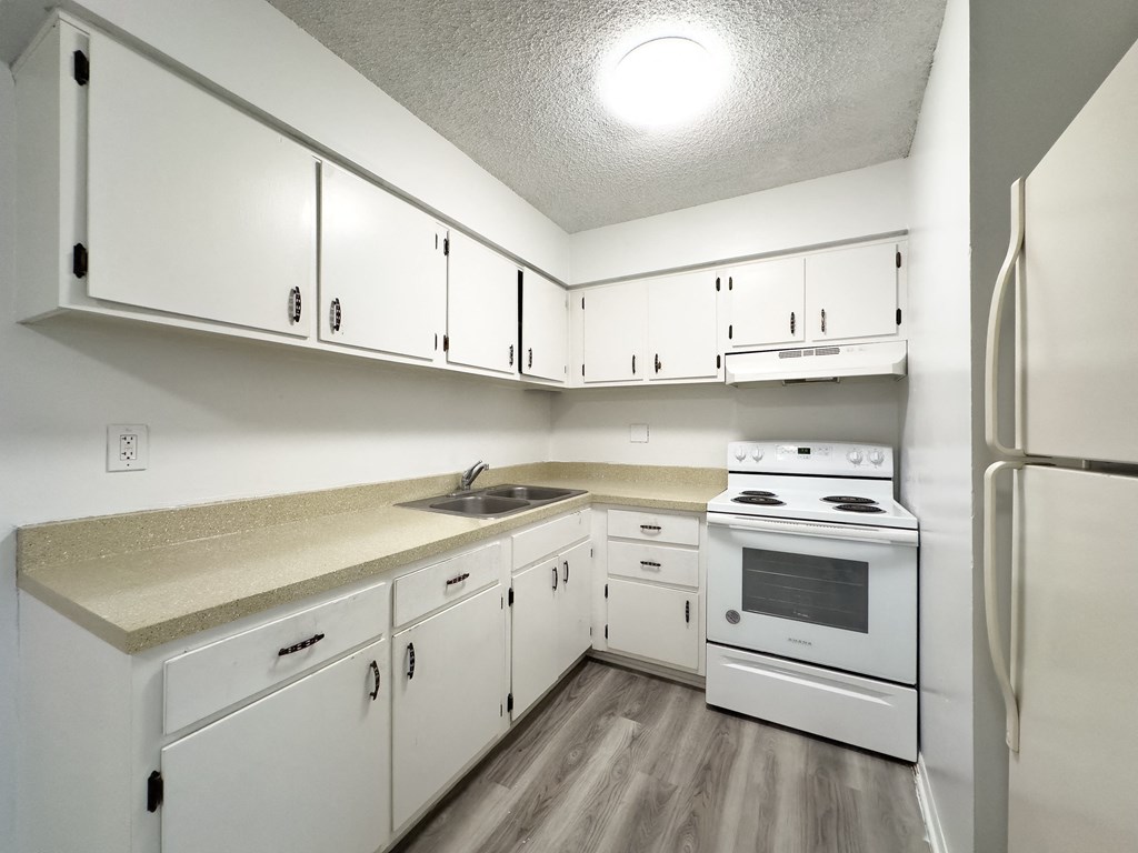 an empty kitchen with white appliances and white cabinets