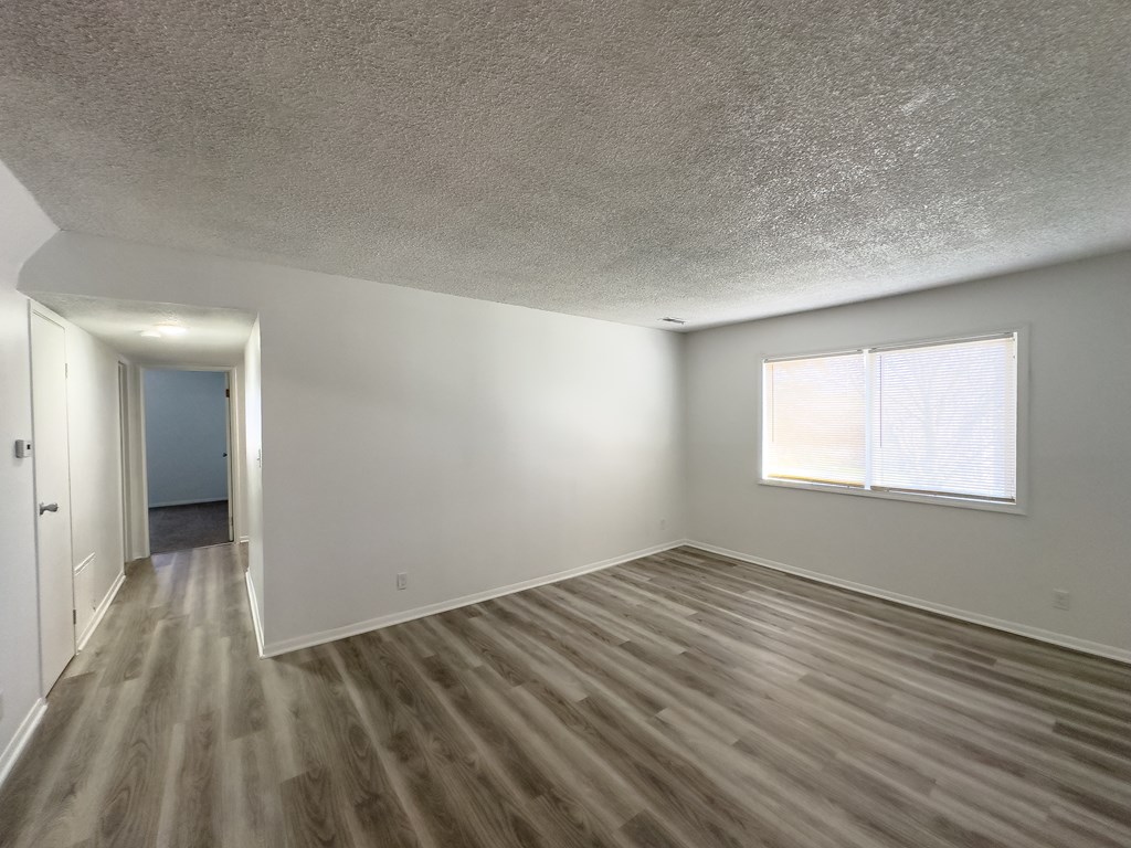 an empty living room with white walls and a window