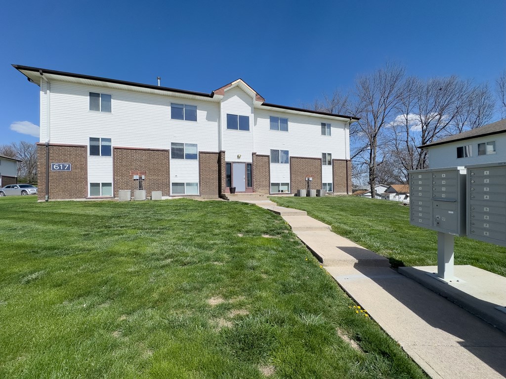 an apartment building with a sidewalk and grass next to Northwest Missouri State University