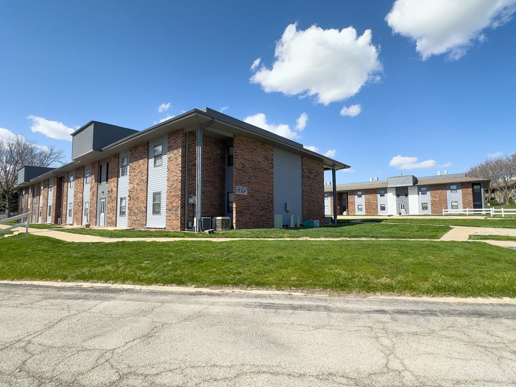 the front of a brick building with green grass
