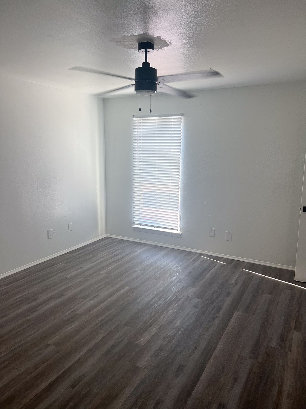 an empty living room with wood floors and a ceiling fan