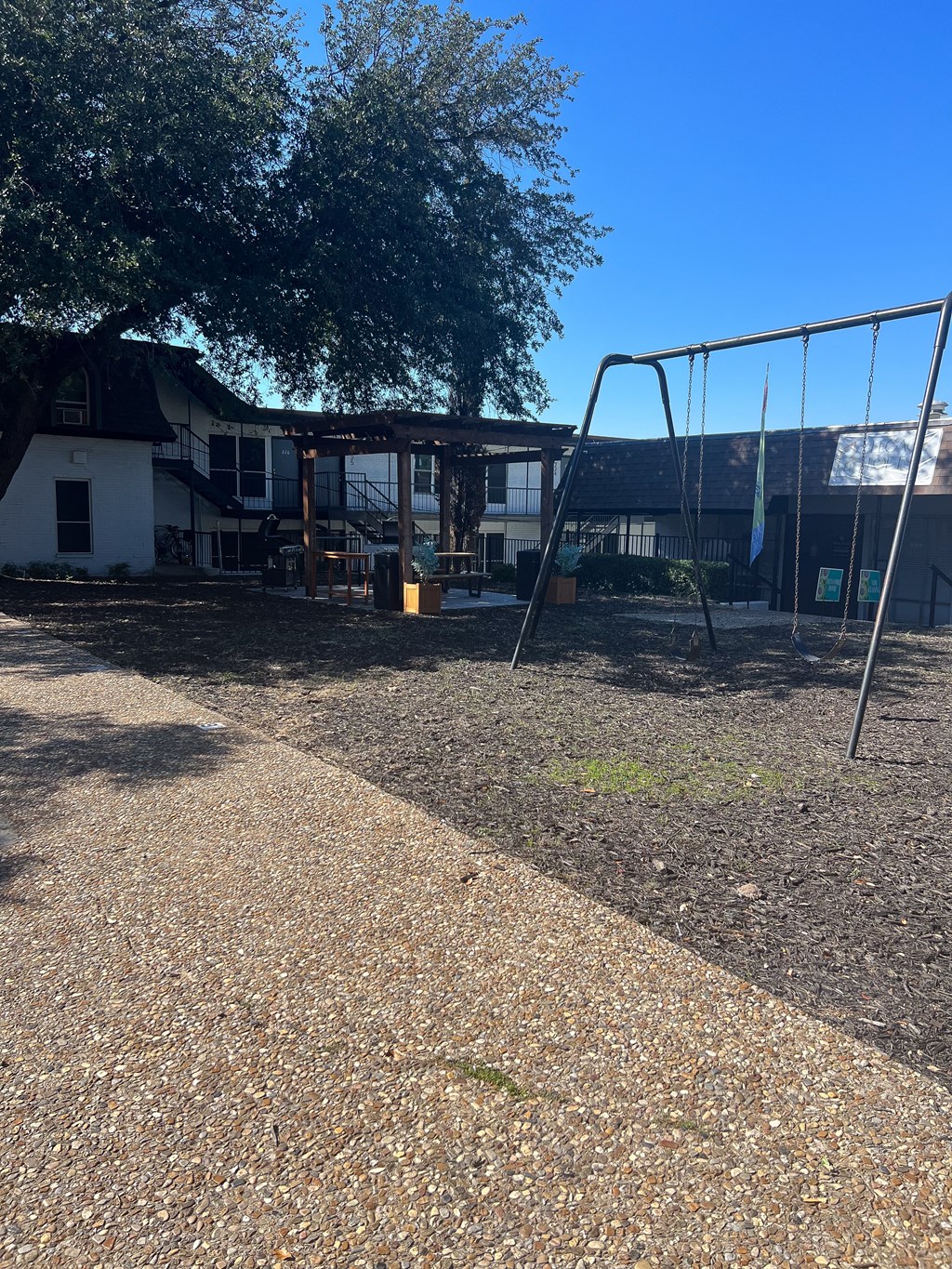 a playground with a swing set in front of a house