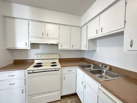 an empty kitchen with white appliances and white cabinets