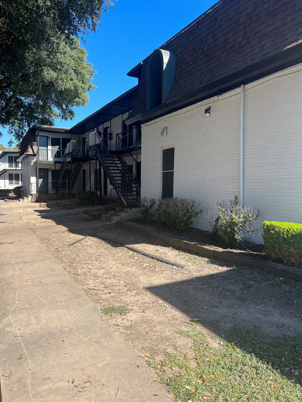 a white building with a black roof and a sidewalk