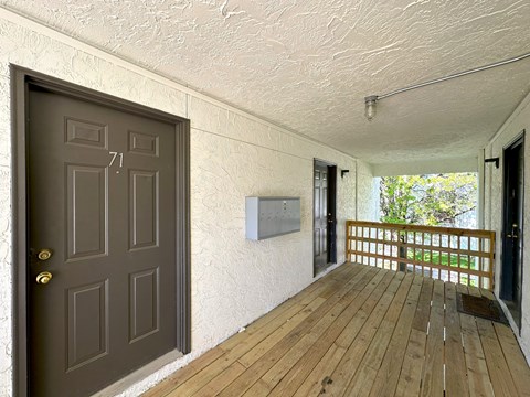 a front porch with a wooden floor and a door with a handle