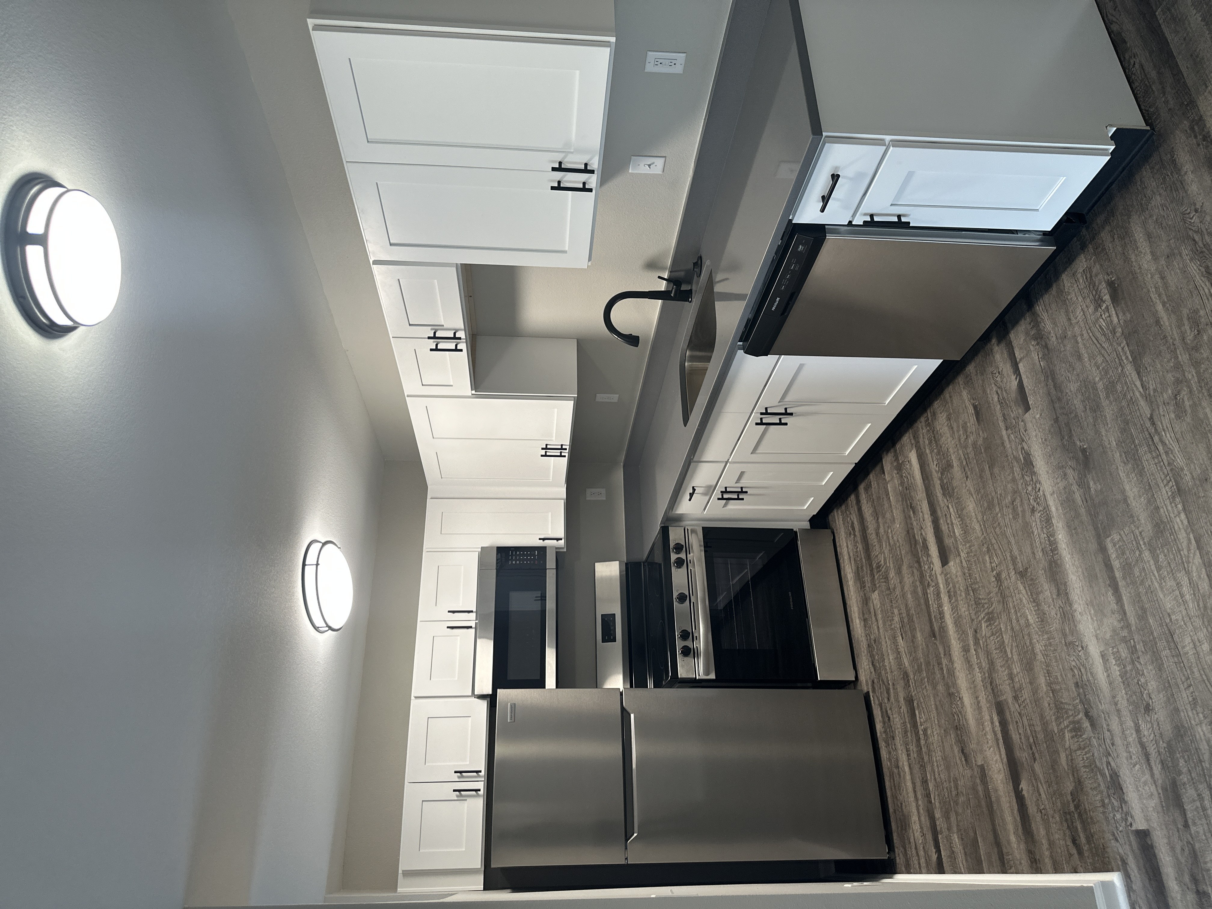 A modern kitchen with a stainless steel refrigerator and a wall-mounted oven.