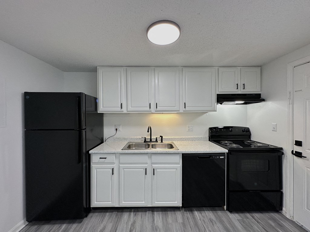 a kitchen with white cabinets and black appliances
