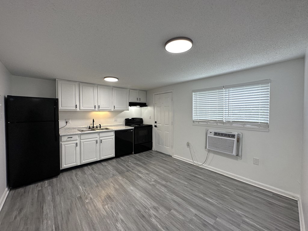 an empty kitchen with white cabinets and black appliances