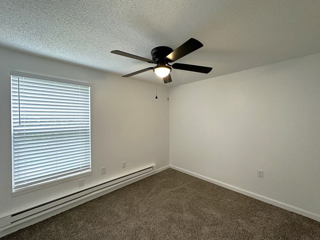 a bedroom with a large window and a ceiling fan