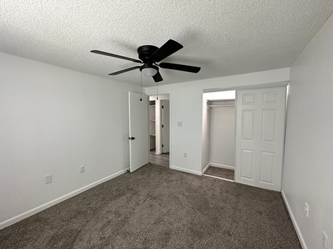 the spacious living room with ceiling fan and carpeting