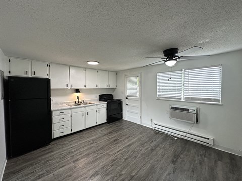 a kitchen with white cabinets and black appliances and a ceiling fan